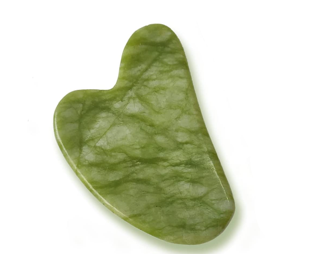 Close up of green jade gua sha on white background
