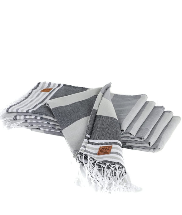 Six grey striped turkish towels folded atop one another displayed on white background