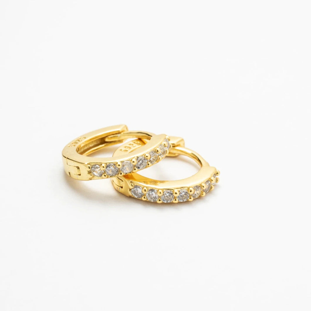 Close up of Amelia CZ gold vermeil huggie earrings set on white background
