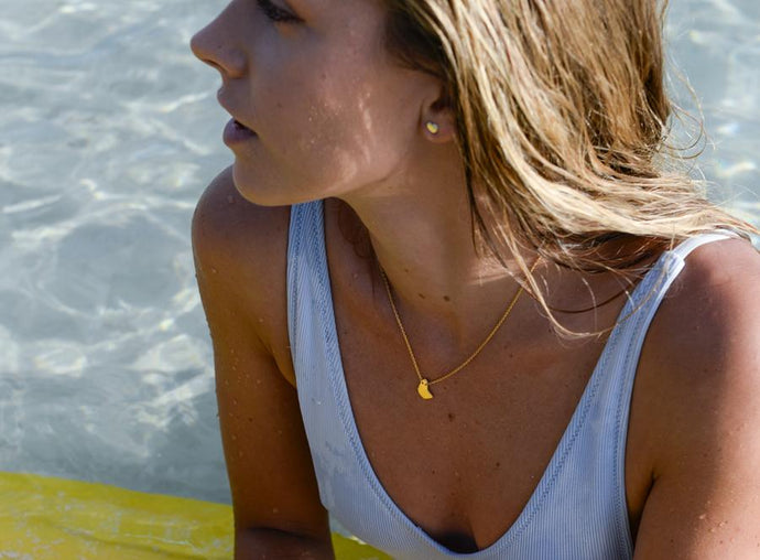 Girl wearing Geo bim necklace in gold vermeil, with water in the background